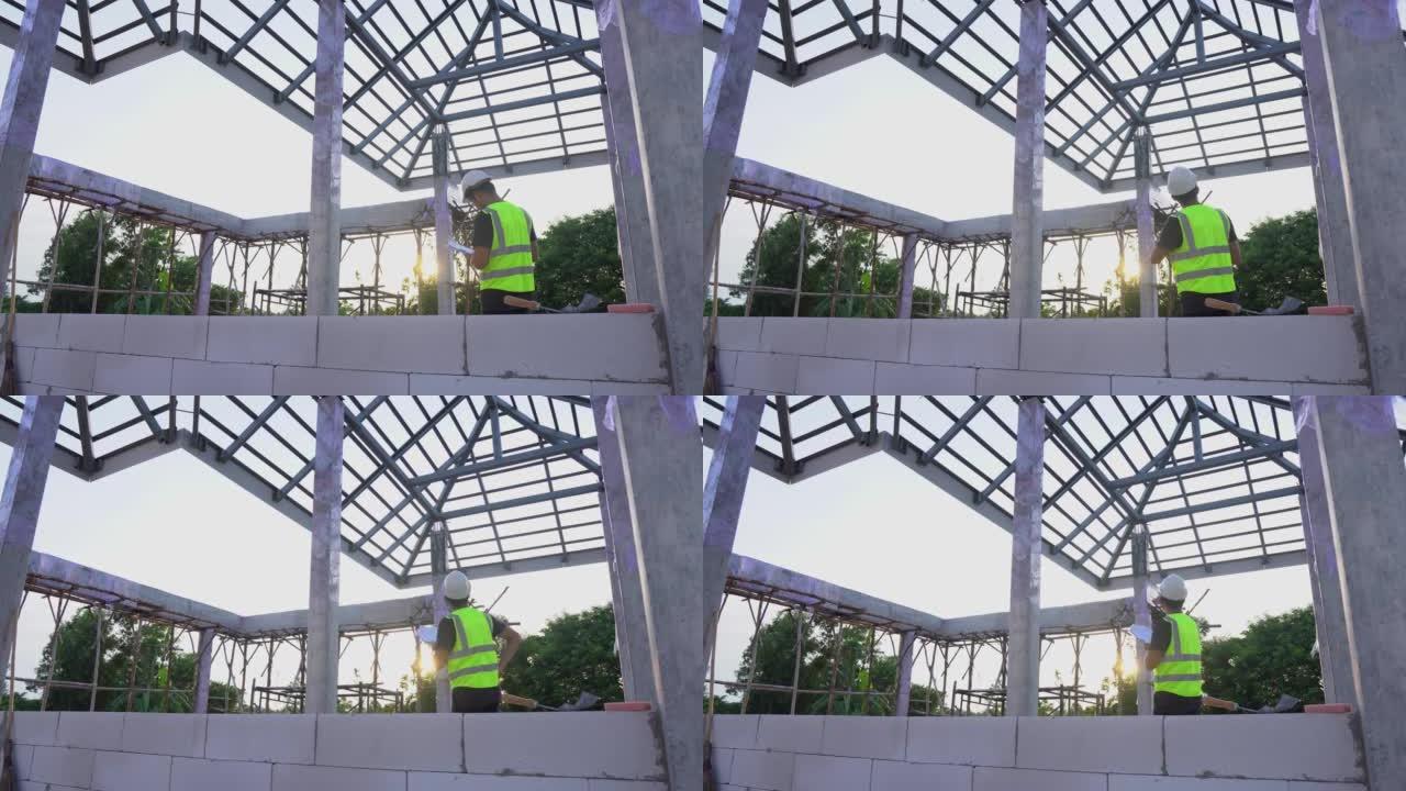 一名工程师技术人员使用蓝图纸观察房屋建筑现场下方的钢屋顶结构。