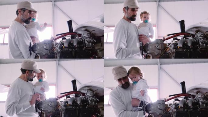 父亲飞机机械师在机场机库展示他的婴儿飞机。
