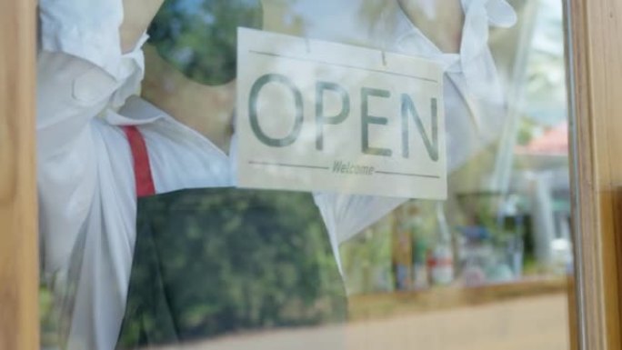 一位小企业主正在旋转一个标志，以显示商店在第一天的开业。独资经营小型咖啡店业务。邻里小企业概念。
