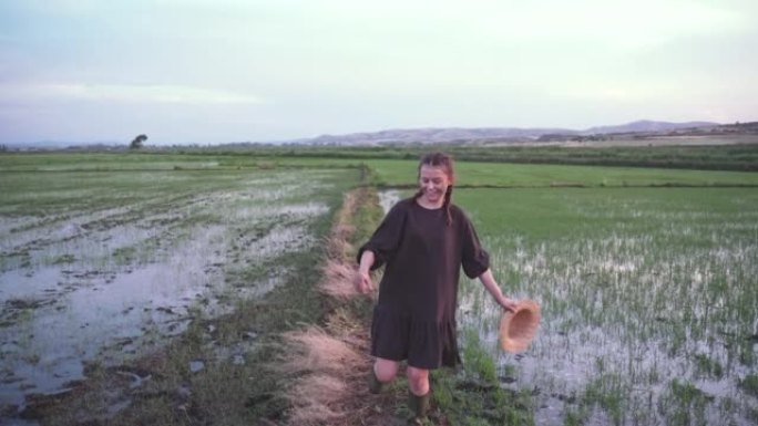 农场女孩在稻田上奔跑，脸上带着米杯