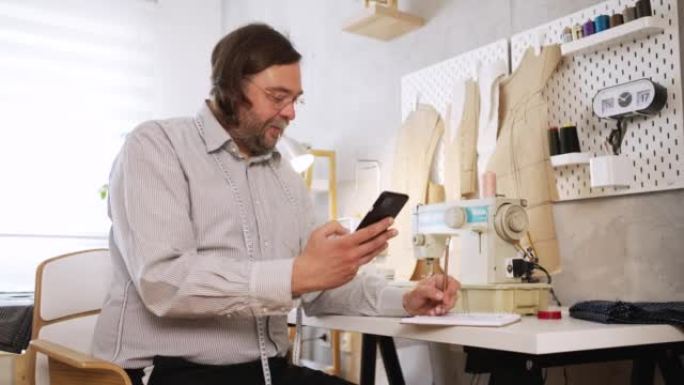 中年白人男性裁缝使用手机的肖像