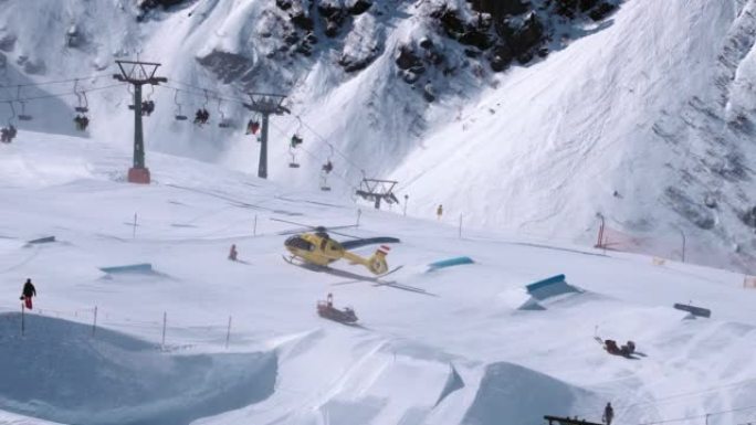 救援直升机降落在斜坡上，帮助滑雪公园的滑雪者。