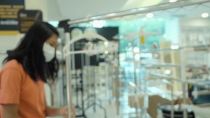戴着口罩的亚洲女孩一起在家具店选择家居装饰晾衣绳，购物生活方式理念
