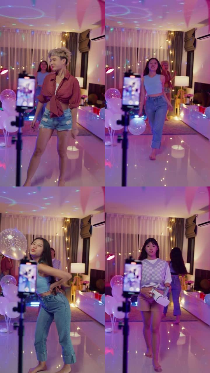 年轻的亚洲女性朋友tiktok通过智能手机制作了她的步行时装秀视频，晚上在五颜六色的家庭聚会上玩得开