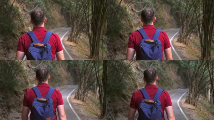 背包客在绿树丛中行走的背包客的背景图。男性旅行者的镜头随后来到国家公园的路上。慢动作