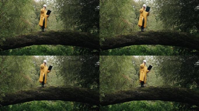 戴着头盔的生态学家站在倒下的树上，他在电话中交谈