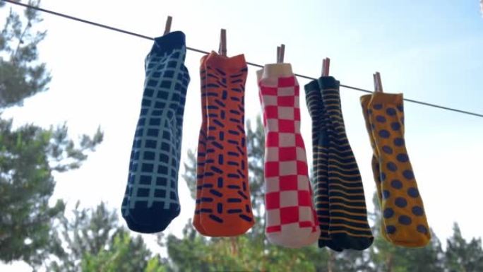 颜色鲜艳的不同图案的男袜用晾衣夹在绳子上晾干。特写。