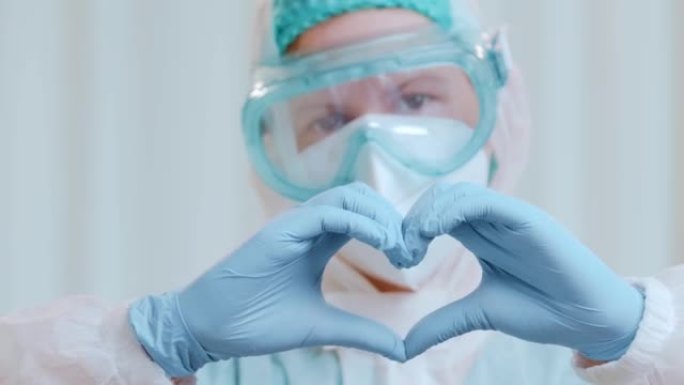 穿着保护性医疗服的医生的特写镜头显示，他的手折叠了一颗心。