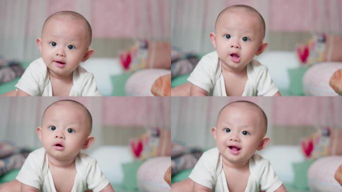 真实的脸部肖像可爱的亚洲新生婴儿在床上爬行或玩耍看着相机，笑容满面。天真的小新婴儿可爱。父母身份和母