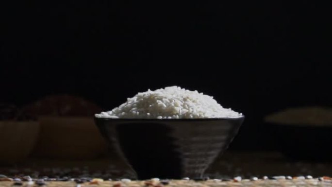 茉莉花白米饭倒入木制桌子上的碗中，有机天然食品概念的未煮熟产品，慢动作镜头