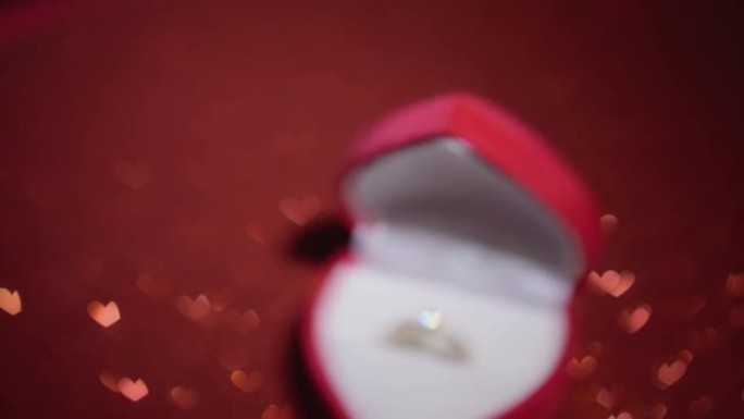 钻石戒指，红色织物背景上有珠宝礼品盒。情人节的金色订婚戒指。结婚求婚的概念。节日和装饰品的浪漫气氛。