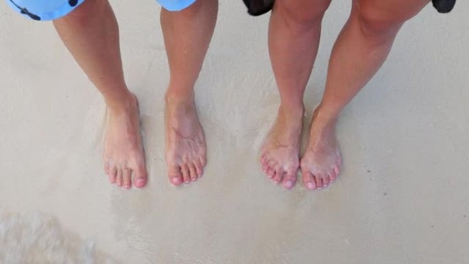 并肩并肩，双脚在沙滩上享受海浪