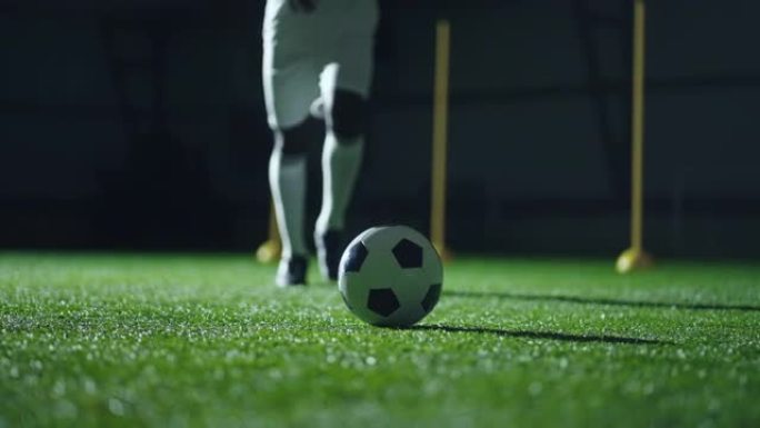 点球，熟练的职业足球运动员的腿和球场上的球的特写镜头，慢动作