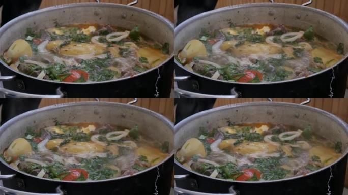 一锅沸腾的亚美尼亚卡什喇嘛的特写。一道菜是肉和蔬菜加很多香草和洋葱。红辣椒和番茄。慢动作