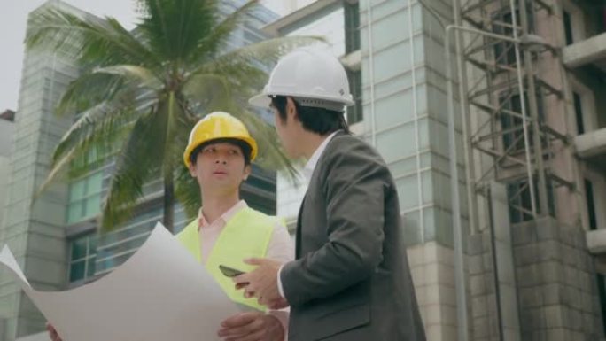 戴着帽子的工程师专心地向持有计划表的工人下达工作命令。
