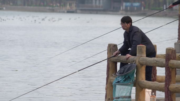 游客在河边凭栏钓鱼