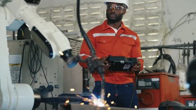 工程师非裔美国人致力于控制和编程制造业中的自动化机器人手臂机器。