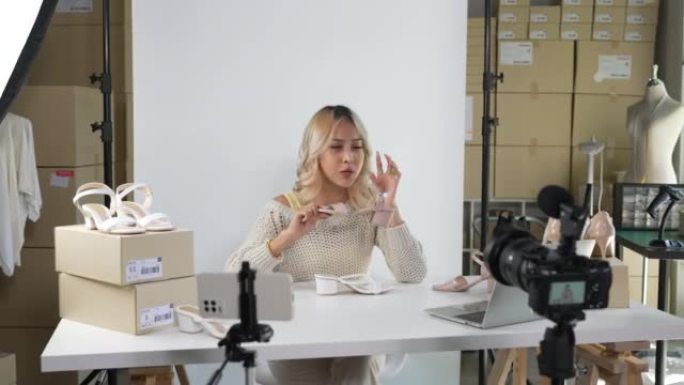 年轻迷人的亚洲女性博客作者或视频博客作者看着相机评论产品。现代女商人使用社交媒体进行营销。社交媒体概