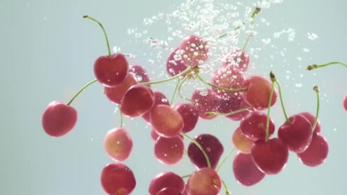 把浆果掉进水里。甜樱桃落入水中慢动作。有机樱桃果落入装有清水的容器中。水和水下气泡的飞溅