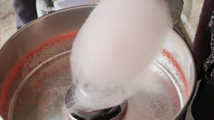 在机器中烹饪棉花糖的过程。糖果线被拧到棍子上，体积增加。儿童零食