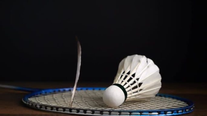 羽毛落在球拍上的慢动作图像，黑色背景上有羽毛球，羽毛球运动项目概念。