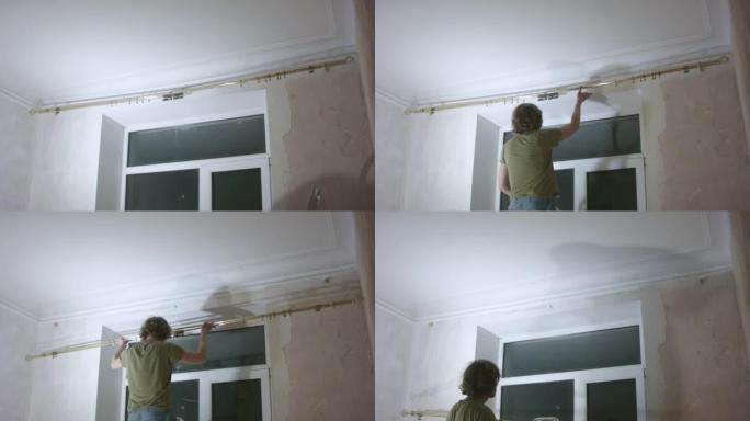 年轻的男性清洁工在家从墙上修理旧百叶窗。