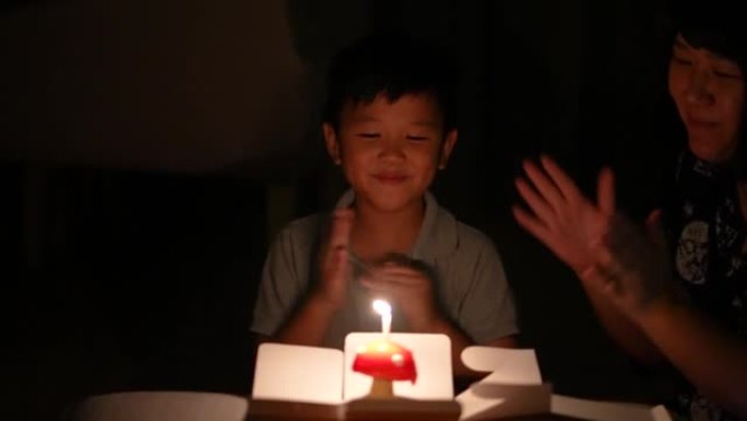 亚洲孩子和他的母亲带着他的生日蛋糕。庆祝和欢乐的概念