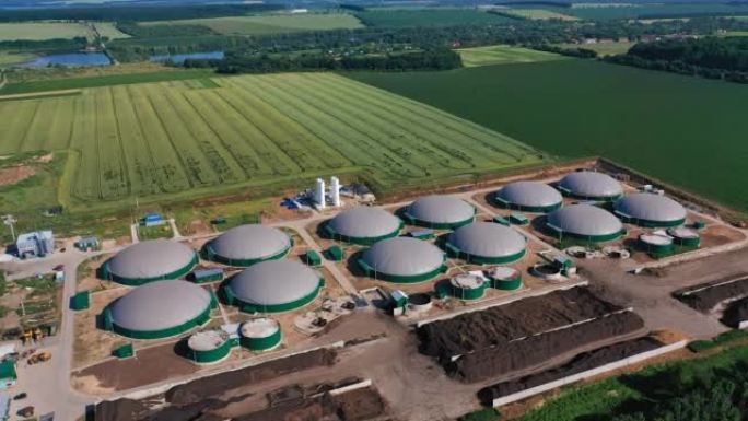 最新沼气生产的圆罐。绿色能源强大工厂的俯视图。背景下的农田。