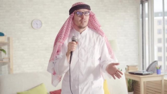 穿着传统服装的快乐阿拉伯男子的肖像在家里的卡拉ok麦克风中唱歌