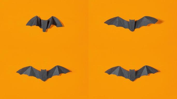 黑色纸蝙蝠在橙色背景上飞行。万圣节假期的概念和贺卡。