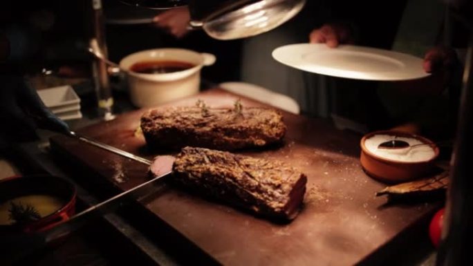 餐厅柜台上的烤肉。餐厅晚餐供应肉类。厨师正在切牛排片。