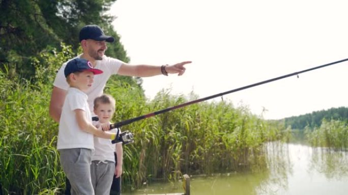 父亲带着小孩儿子站在木桥或码头上抓鱼。家庭爸爸和孩子们一起度过休闲时光露营教钓鱼