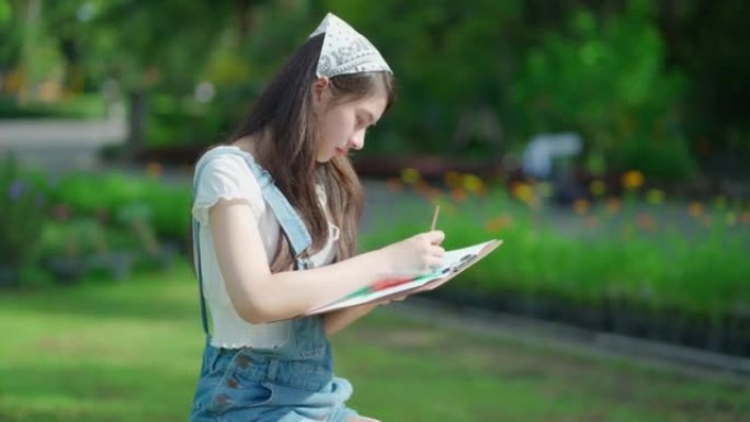 迷人的年轻漂亮女孩的肖像坐在公共花园中，在夏季绘画或绘画。绿色春天公园的灵感。假期中的艺术和放松