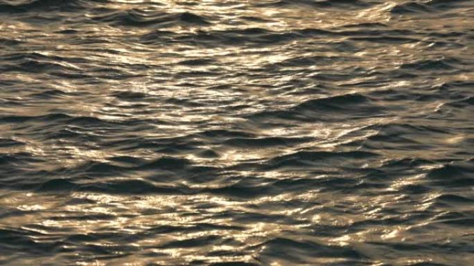夕阳下的海水在慢动作。太阳在水中的许多闪亮反射。这是在阳光明媚的日子里有小涟漪的海洋的特写镜头。10