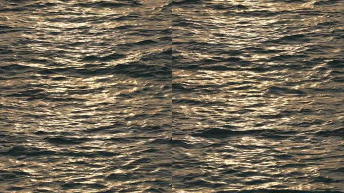 夕阳下的海水在慢动作。太阳在水中的许多闪亮反射。这是在阳光明媚的日子里有小涟漪的海洋的特写镜头。10