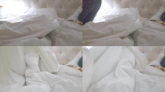 4在视频中，一个穿着睡衣的女人晚上上床睡觉，用白色毯子盖住自己，卧室的内部有床和台灯