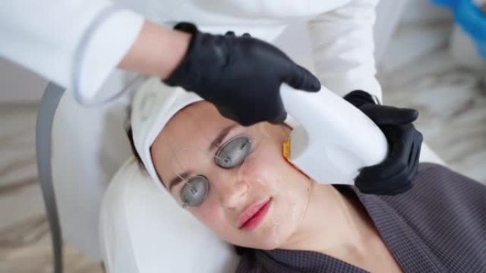 美容程序在现代美容诊所中，专家美容师正在使用光疗仪