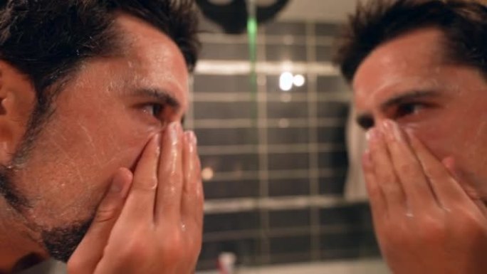 人在浴室镜子前洗脸的男人晚上使用洗面奶