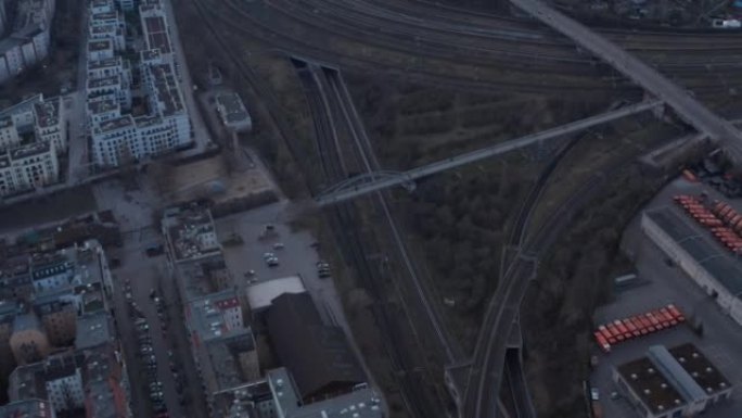空铁路线的空中慢动作视图，人们步行在德国柏林的住宅和清晨停放的车辆附近的桥梁上行走