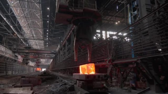 带有爪子的起重机将加热到红色的钢锭抬起。钢坯的生产。冶金厂。滚动商店。经营理念、现代钢铁生产技术