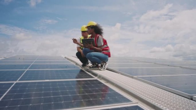 夫妇工程师检查在阳光下在屋顶上安装太阳能电池板。可再生能源的概念。