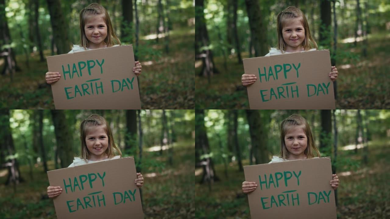 小女孩微笑着在森林里拿着海报的肖像。用4K红氦相机拍摄。