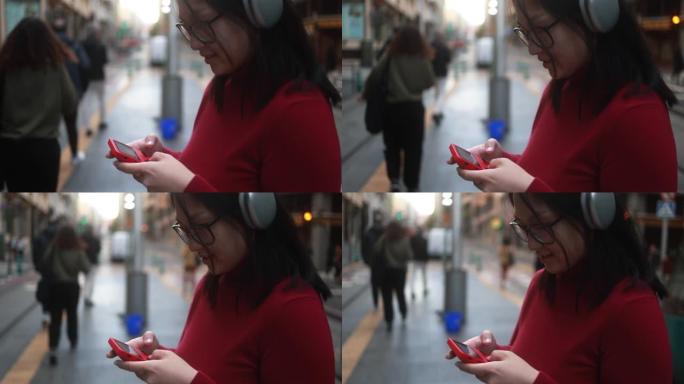年轻的亚洲女性用老式设备玩游戏，用无线耳机听音乐播放列表 -- 城市生活理念