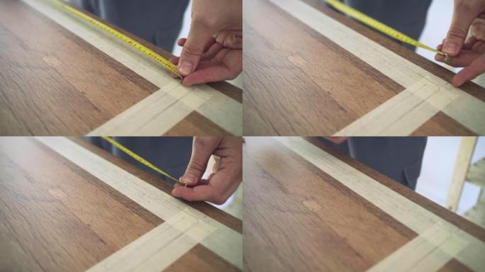无法识别的木匠用卷尺测量木桌的长度