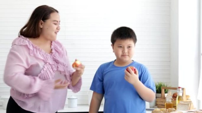 胖妈妈和胖男孩一起吃新鲜苹果，健康水果