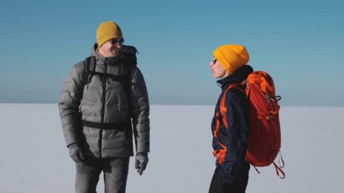 两个背着背包的旅行者穿过雪场。慢动作