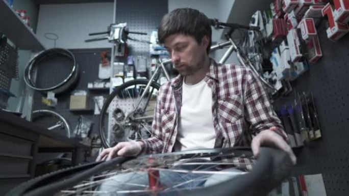 在自行车商店更换自行车内胎和轮胎。自行车修理工在工作中修理车轮。自行车机械师在自行车店工作。服务和自