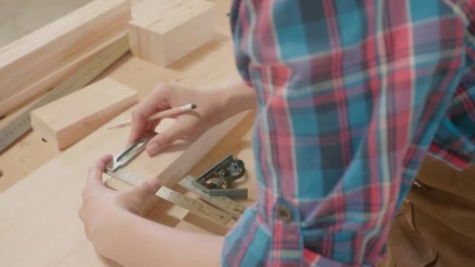 用铅笔和尺子用木板工作的女木匠