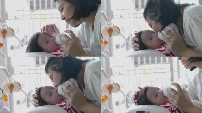 快乐的亚洲妈妈正在家里用奶瓶哺乳。