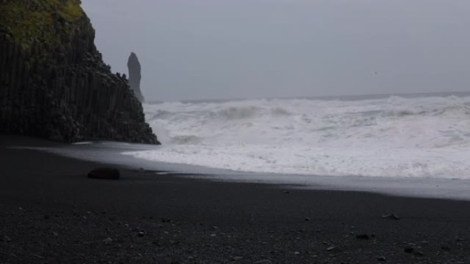 黑沙滩上的海浪撞击岩石